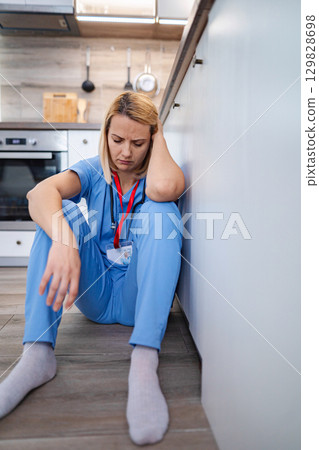 Exhausted doctor sitting on the floor in the kitchen 129828698