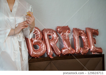 Bride Getting Ready with Champagne and Balloons: Luxury Wedding Preparation Scene with Rose Gold Decor and Silky Robe. 129828711