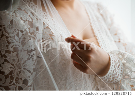 Intimate Bridal Moment: Woman Adjusting Veil, Delicate Lace Robe, Soft Lighting, Wedding Preparations, Romantic, White, Textured Fabric, Close-Up Shot. Intimate Bridal Moment: Woman Adjusting Veil, Delicate Lace Robe, Soft Lighting, Wedding Preparations, Romantic, White, Textured Fabric, Close-Up Shot. 129828715