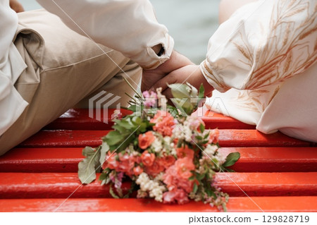 Romantic Wedding Ceremony Hands Joined Over Bouquet Red Bench Natural Light Rustic Style Celebration of Love Commitment Ceremony Details. Romantic Wedding Ceremony Hands Joined Over Bouquet Red Bench Natural Light Rustic Style Celebration of Love Commitment Ceremony Details. 129828719