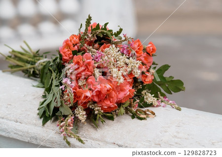 Coral Wedding Bouquet with Rings on Stone Ledge. Romantic Floral Arrangement, Peach-Colored Roses, Vintage Style, Ceremony Details, Love and Commitment Coral Wedding Bouquet with Rings on Stone Ledge. Romantic Floral Arrangement, Peach-Colored Roses, Vintage Style, Ceremony Details, Love and Commitment 129828723
