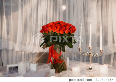 Romantic Red Rose Bouquet and Candles on Table Setting for Valentines Day Love, Celebration, Luxury Decor in Elegant White Room Romantic Red Rose Bouquet and Candles on Table Setting for Valentines Day Love, Celebration, Luxury Decor in Elegant White Room 129828737