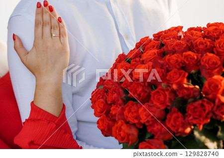 Romantic Proposal Scene with Diamond Ring, Red Roses Bouquet, Happy Couple, Warm Lighting, White Shirt, Celebrating Love, Engagement Photography Romantic Proposal Scene with Diamond Ring, Red Roses Bouquet, Happy Couple, Warm Lighting, White Shirt, Celebrating Love, Engagement Photography 129828740