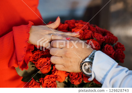 Romantic Proposal with Red Roses: Couple Holding Hands with Wedding Ring, Love, Celebration, Jewelry, and Passionate Moment in Vibrant Colors 129828743