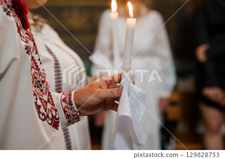 Orthodox Church Ritual with Candles: Traditional Eastern European Ceremony, Liturgical Celebration, White Robes, Red Embroidery, Soft Lighting 129828753