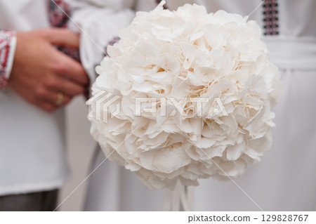 White Hydrangea Bouquet Held by Hands in Traditional Clothing, Rustic Wedding Floral Arrangement, Cream Tones, Textured Style White Hydrangea Bouquet Held by Hands in Traditional Clothing, Rustic Wedding Floral Arrangement, Cream Tones, Textured Style 129828767