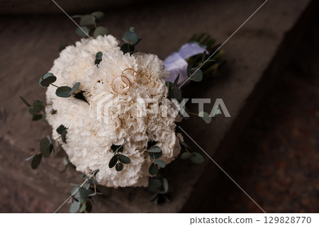 Wedding Rings Resting on White Carnation Bouquet with Eucalyptus and Lavender. Rustic Romance, Floral Arrangement, Ceremony Details 129828770