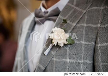 Groom's Boutonniere Detail: Gray Suit, White Carnation, Wedding Attire, Formal Style, Close-Up Shot, Elegant Celebration, Textured Lapel Groom's Boutonniere Detail: Gray Suit, White Carnation, Wedding Attire, Formal Style, Close-Up Shot, Elegant Celebration, Textured Lapel 129828779