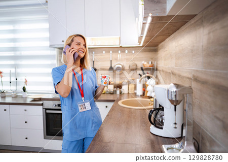 Young female doctor is enjoying her coffee break at home, talking on the phone 129828780