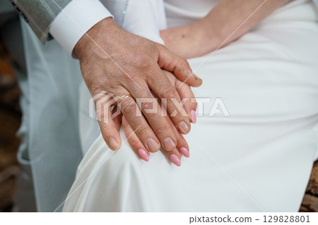 Elderly Couple Holding Hands With Wedding Rings, White Attire, Tender Love, Generations, Warm Color Palette, Close-Up Shot, Emotional Connection 129828801