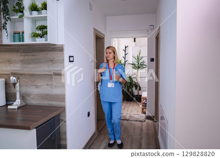 Female doctor walking in a hospital corridor with a backpack and a drink Female doctor walking in a hospital corridor with a backpack and a drink 129828820