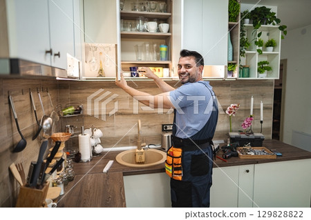 Handyman installing led strip lights under kitchen cabinets 129828822