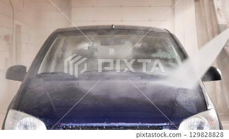 Car wash worker cleaning windshield with high pressure water jet Car wash worker cleaning windshield with high pressure water jet 129828828