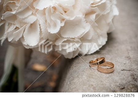 Romantic Wedding Rings with White Carnations Bouquet. Symbolizing Love, Commitment and Celebration in Soft Tones. Romantic Wedding Rings with White Carnations Bouquet. Symbolizing Love, Commitment and Celebration in Soft Tones. 129828876