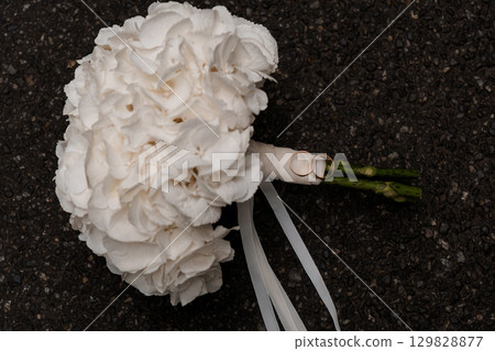 Wedding Bouquet and Rings - White Carnations with Gold Bands on Dark Asphalt, Romantic Marriage Symbol, Elegant Still Life Photography Wedding Bouquet and Rings - White Carnations with Gold Bands on Dark Asphalt, Romantic Marriage Symbol, Elegant Still Life Photography 129828877