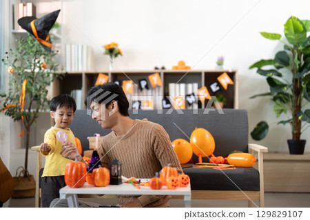 Halloween Celebration. Father and son enjoying festive pumpkin decorations together. 129829107