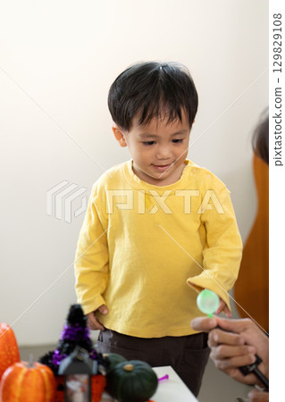 Young boy excitedly exploring Halloween-themed toys with father 129829108