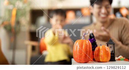 Halloween Spirit. Father and son enjoying pumpkin crafts and laughter. Halloween Spirit. Father and son enjoying pumpkin crafts and laughter. 129829112