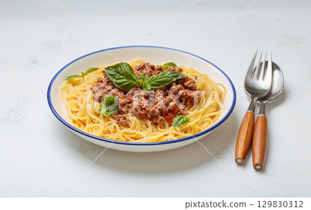 Italian spaghetti bolognese with basil and parmesan on plate on white background top view Italian spaghetti bolognese with basil and parmesan on plate on white background top view 129830312