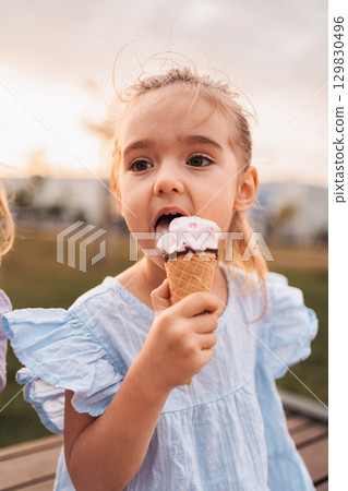 Little girl enjoying ice cream cone outdoors in summer 129830496