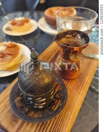 Enjoying traditional Arabic coffee served on warm sand with sweet pastries Enjoying traditional Arabic coffee served on warm sand with sweet pastries 129830955