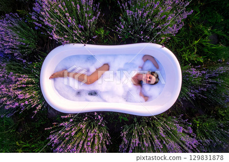 a woman immersed in a bathtub in a flowery meadow 129831878