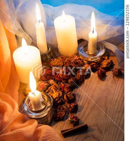 Candles and dried rosebuds on the table Candles and dried rosebuds on the table 129832356