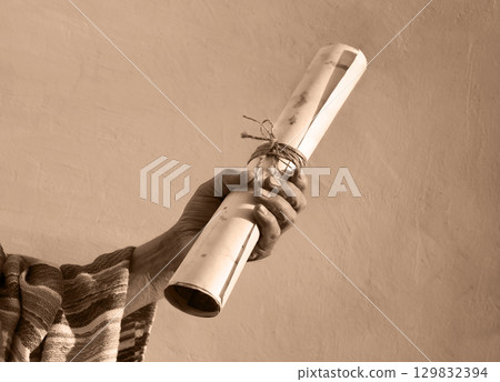 Male hand holding an old scroll Male hand holding an old scroll 129832394