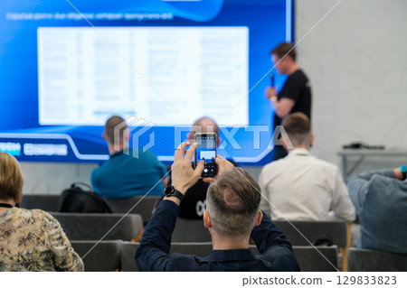 Man capturing presentation on smartphone during educational conference Man capturing presentation on smartphone during educational conference 129833823