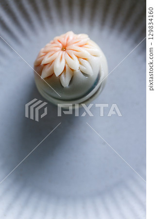 A piece of delicious Japanese confectionery on off white ceramic plate on wooden table. 129834160