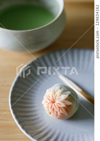 Cup of fresh matcha tea, green tea and Nerikiri, Japanese confectionery, on wooden table. 129834162