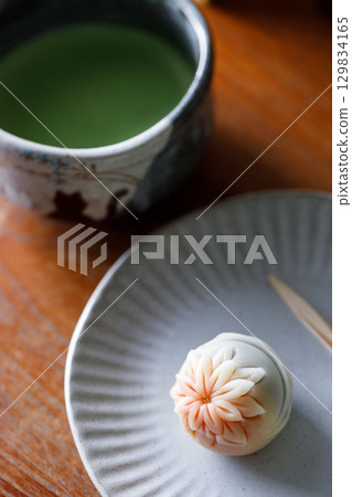 Cup of fresh matcha tea, green tea and Nerikiri, Japanese confectionery, on wooden table. Cup of fresh matcha tea, green tea and Nerikiri, Japanese confectionery, on wooden table. 129834165