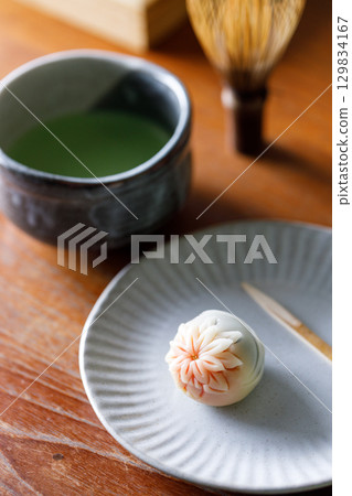 Cup of fresh matcha tea, green tea and Nerikiri, Japanese confectionery, on wooden table. 129834167