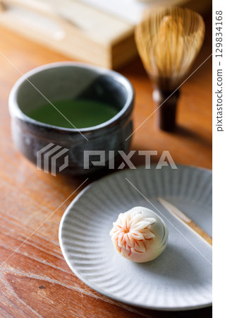 Cup of fresh matcha tea, green tea and Nerikiri, Japanese confectionery, on wooden table. Cup of fresh matcha tea, green tea and Nerikiri, Japanese confectionery, on wooden table. 129834168