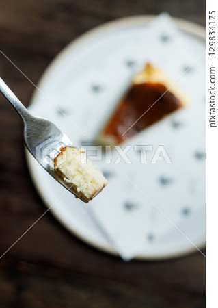 A small piece of cheese cake on a fork. A small piece of cheese cake on a fork. 129834175