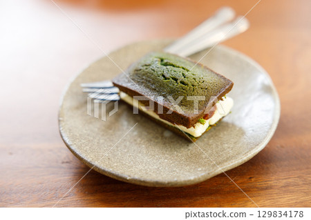 A piece of Cheese and Matcha and red bean paste financier, small French almond cake, on wooden table. A piece of Cheese and Matcha and red bean paste financier, small French almond cake, on wooden table. 129834178