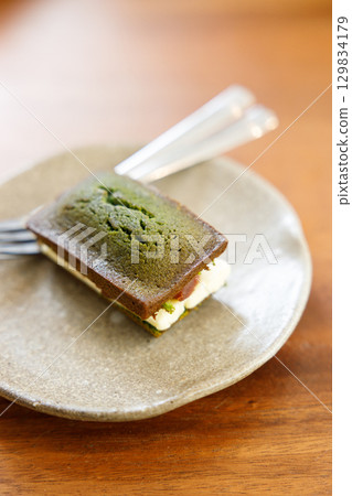 A piece of Cheese and Matcha and red bean paste financier, small French almond cake, on wooden table. A piece of Cheese and Matcha and red bean paste financier, small French almond cake, on wooden table. 129834179