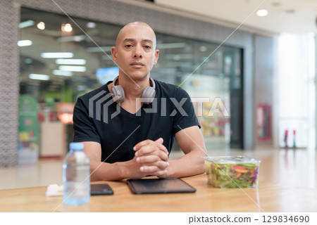 Man eating healthy salad in food court, health and wellness lifestyle 129834690