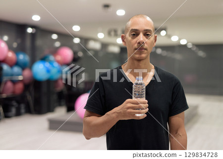 Hispanic bald man athlete in gym doing fitness workout training and holding water bottle Hispanic bald man athlete in gym doing fitness workout training and holding water bottle 129834728