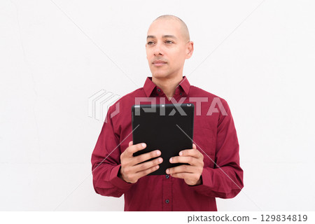 Man using digital tablet computer in burgundy shirt against white background 129834819