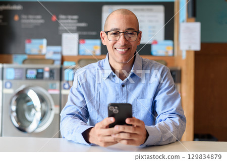 Man Using Phone Inside Urban Laundry Shop 129834879