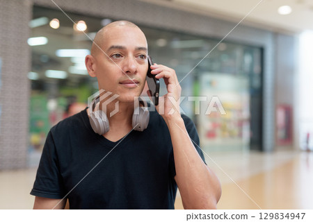 Man talking on mobile phone alone in mall food court, digital lifestyle concept Man talking on mobile phone alone in mall food court, digital lifestyle concept 129834947