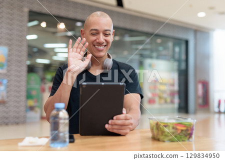 Man using tablet while eating salad in mall, digital lifestyle and wellness Man using tablet while eating salad in mall, digital lifestyle and wellness 129834950