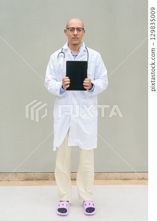 Full Length Portrait of Hispanic Male Doctor in Lab Coat using Tablet Computer Full Length Portrait of Hispanic Male Doctor in Lab Coat using Tablet Computer 129835009