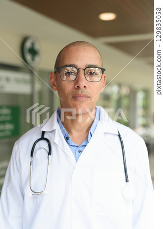 Doctor Standing Outside Medical Clinic Wearing White Lab Coat Doctor Standing Outside Medical Clinic Wearing White Lab Coat 129835058