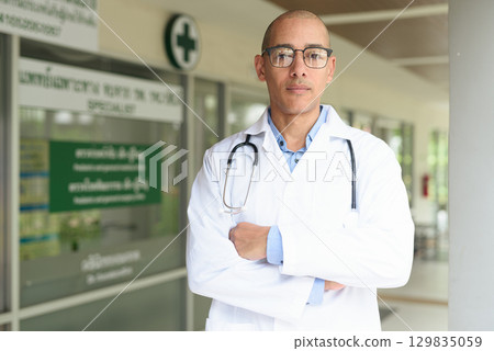 Doctor Standing Outside Medical Clinic Wearing White Lab Coat Doctor Standing Outside Medical Clinic Wearing White Lab Coat 129835059
