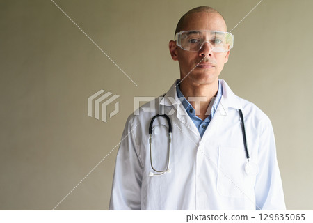 Male Scientist in Lab Coat with Safety Glasses on Plain Background Male Scientist in Lab Coat with Safety Glasses on Plain Background 129835065