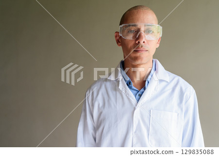 Male Scientist in Lab Coat with Safety Glasses on Plain Background 129835088