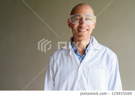 Male Scientist in Lab Coat with Safety Glasses on Plain Background 129835089