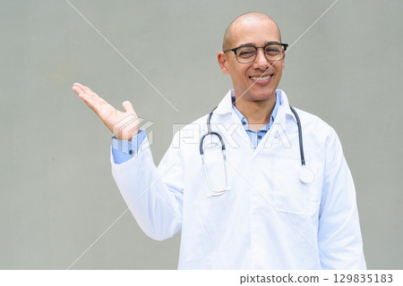 Hispanic Happy Male Doctor in Lab Coat with Stethoscope on Plain Background Smiling 129835183